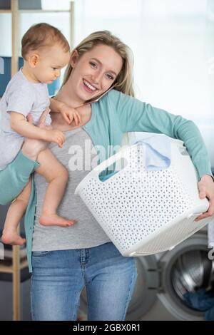 Multitasking Frau beim Wäschewaschen am Telefon mit Baby Stockfoto