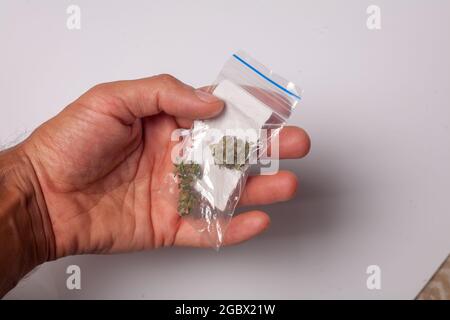 Ein Paket mit illegalem Cannabis in der Hand. Medizinisches Marihuana zur verschreibungspflichtigen Behandlung. Drogenhändler verkauft Marihuana-Süchtige. Stockfoto