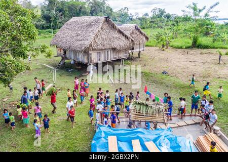 SANTA MARIA DE ANGOTEROS, PERU - 15. JULI 2015: Kinder eines Dorfes Santa Maria de Angoteros begrüßen ein Frachtschiff auf einem Fluss Napo. Stockfoto