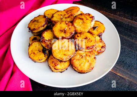 Sweet Caramel Cinnamon Baked Plantains: Ein Teller mit gebackenen Plantains, bedeckt mit Zimt und karamellisiertem Zucker Stockfoto