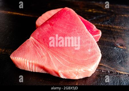 Rohe Thunfischsteaks auf dunklem Holz Hintergrund: Nahaufnahme von ungekochten Thunfischsteaks auf einem Holztisch Stockfoto