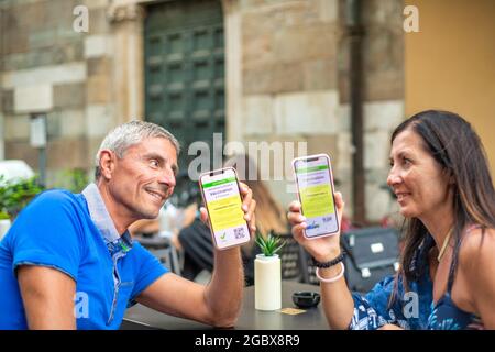 Ein glückliches Paar saß an einem Restauranttisch mit einem grünen Pass. Mann und Frau sind bereit für eine Reise mit Screenshots der Impfung Stockfoto