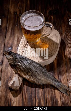 Bier mit getrocknetem Fisch und Snacks auf einem Holztisch. Stockfoto