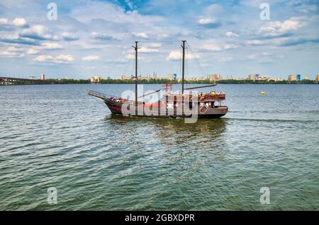 Dnipro, Ukraine - 14. September 2019: Das als Piratenschiff stilisierte Vergnügungsschiff schwimmt vor dem Hintergrund der Küste und der Brücke entlang des Flusses Stockfoto