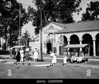 EINE GRUPPE VON ELEGANT SPORTLICH GEKLEIDETEN MÄNNERN UND FRAUEN AUS DEN 1930ER JAHREN, DIE AN BOWLS ODER RASENBOWLS IM COUNTRY CLUB TEILNEHMEN UND DIESE GENIESSEN - ASP AP10 801 ASP001 HARS JOY LIFESTYLE ÄLTERE FRAUEN GESUNDHEIT COPY SPACE FREUNDSCHAFT GANZKÖRPERFITNESS DAMEN SPORTLICHE FITNESS PERSONEN BOWLS MÄNNER SPORTLICH SENIOR MAN SENIOR ADULT B&W SENIOR WOMAN OLD AGE OLDSTERS OLDSTER FREIZEITSTRATEGIE UND GENIESSEN ERHOLUNG IM FREIEN LAND CLUB AT IN VON AUF GEHOBENE ÄLTESTEN WOHLHABENDEN ELEGANT STERNE UND STREIFEN STILVOLLE UNGEWÖHNLICHE ALTE PRACHT ODER BOWLING GRÜN KITTY SPIELTE ROT WEISS UND BLAU ENTSPANNUNG ZWEISAMKEIT GUT-ZU-TUN SCHWARZ UND WEISS Stockfoto