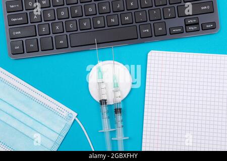 Impfungs-, Immunologie- oder Reimpfungskonzept - zwei medizinische Spritze, die auf dem blauen Tisch in der Arztpraxis in einem Krankenhaus oder einer Klinik liegen. Geöffneter leerer Editor - Mock Up with Copy Space Stockfoto