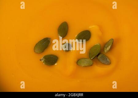 Kürbiscremesuppe mit Kürbiskernen in einer schwarzen Schüssel. Grauer Steinhintergrund. Draufsicht Stockfoto