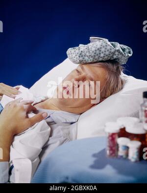 1970ER KRANKE MANN PATIENT IM BETT EISBEUTEL AUF DEM KOPF BEISTELLTISCH MIT PILLEN MEDIKAMENTE FIEBER THERMOMETER LIEGEND IN SEINEM MUND - KS11991 HAR001 HARS PILLEN TRAURIGKEIT GESUNDHEIT LEIDEN PRÄVENTION KOPF UND SCHULTERN FIEBER HOHEN WINKEL SEINE HEILUNG DIAGNOSE GESUNDHEITSVERSORGUNG BEEINTRÄCHTIGUNG BEHANDLUNG KONZEPTUELL SCHLECHTE GESUNDHEIT ERKRANKT MID-ADULT MANN MID-ADULT MANN KAUKASISCHE ETHNIZITÄT KRANKHEIT HAR001 MEDIKAMENTE ALTMODISCH Stockfoto