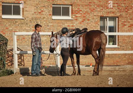 Mädchen, die sich bereit machen, an einem Sommertag im Stall ein Pferd zu reiten Stockfoto