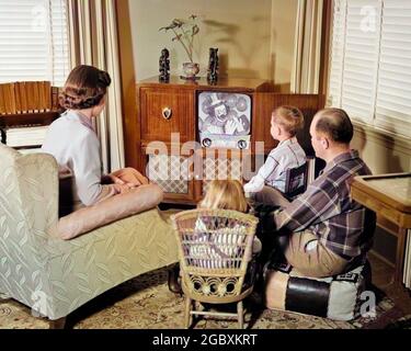 RÜCKBLICK AUF DIE 1950ER JAHRE DER 4-KÖPFIGEN FAMILIE, DIE SICH UM DAS FERNSEHGERÄT VERSAMMELT UND CLOWN MIT BALLONS BEOBACHTET - R10116C HAR001 HARS CLOWN 4 FARBE BEZIEHUNG MÜTTER ALTE ZEIT NOSTALGIE BRUDER MEDIEN ALTE MODE SCHWESTER GERÄT ELEKTRISCHE JUGENDLICHE KOMMUNIKATION INFORMATION SÖHNE FAMILIEN ELTERNSCHAFT FRAUEN VERHEIRATET BRÜDER BEZIEHUNG EHEPARTNER EHEMÄNNER ERWACHSEN ZU HAUSE LEBEN KOMMUNIKATION KOPIE RAUM HALBE LÄNGE DAMEN TÖCHTER MAKE-UP PERSONEN CHARAKTER MÄNNER PRODUKT UNTERHALTUNG GESCHWISTER SCHWESTERN VÄTER MASSENMEDIEN PARTNER VÄTERLICHE FERNSEHER VATERSCHAFT MÜTTERLICHE MAKE-UP RUNDFUNK FREIZEIT BEOBACHTER WOHNZIMMER UND VÄTER MACHEN NACH OBEN Stockfoto