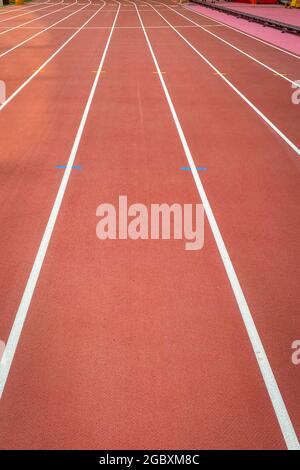 Lane auf einer roten Leichtathletik-Strecke mit weißen Linien und blauen und gelben Markierungen Stockfoto