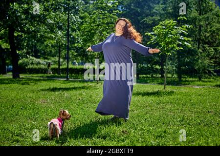 Plus size Frau tanzen auf Rasen in langen Sommerkleid. Stockfoto