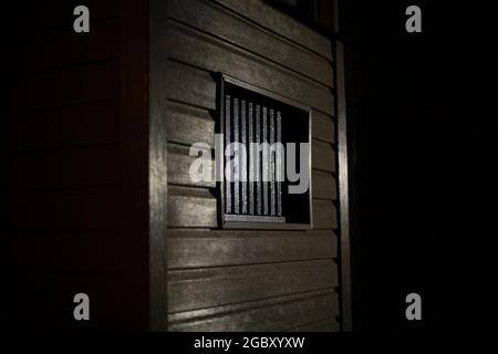 Fenster im Dunkeln. Gitter am Fenster zum Keller. Lüftungsloch im Haus. Stockfoto