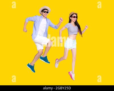 Glückliches junges Paar in Sonnenbrillen und Hüten. Isoliert auf gelbem Hintergrund. Stockfoto