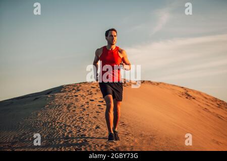 Trailrunner Athlet Laufen Mann in Wüstensand Dun in der Hitze des Sommers Sonnenuntergang Tag Stockfoto