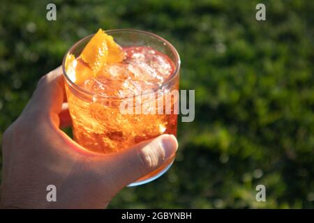 Eine Hand mit einem Whisky-Cocktail aus Orange, serviert in einer Außenbar in Bodega Bay, Kalifornien Stockfoto