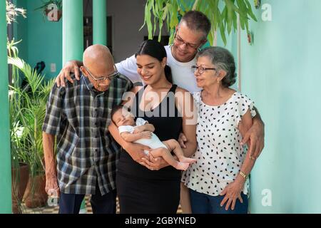 Foto einer Gruppe von Menschen. Ein Baby in den Armen einer jungen Frau, eines Mannes und eines älteren Paares Stockfoto