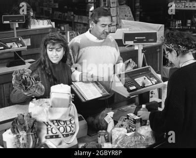 Austin Texas USA, um 1990: Hispanische Familie an der Kasse des örtlichen Reformhauses Whole Foods. MR es-0437 Farbe erhältlich. ©Bob Daemmrich Stockfoto