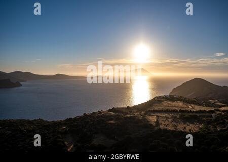 Sonnenaufgang über dem ägäischen Mittelmeer. Kykladen Griechenland. Letzte Sonnenstrahlen über dem glitzernden Meer, goldenem Land. Sommerferien und Entspannung. Sonnenstrahlen Stockfoto