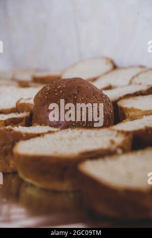 Burger-Brot auf ein Schneidebrett gelegt. Schneidebrett mit Brotscheiben mit Sesamsamen für die Herstellung von Burgern. Sandwiches mit Sesam für gemahlenen Mea Stockfoto