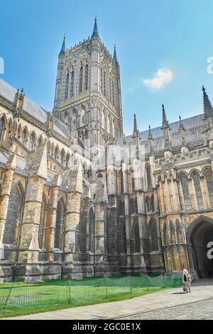 Eine ältere Frau passiert den südlichen Querschiff und zentralen Turm der mittelalterlichen Kathedrale in Lincoln, England. Stockfoto