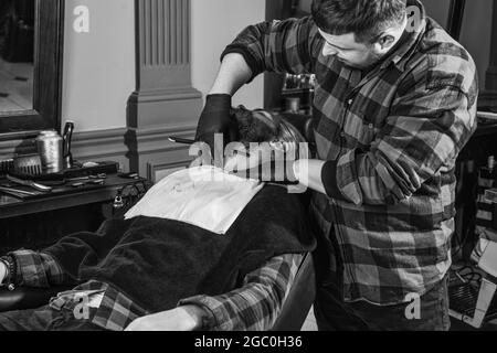 Friseur mit männlichem Kunden. Hipster mit gefärbtem Bart und Schnurrbart. Mann wollen neue Frisur. Männliche Schönheit und Mode. Reifer Mann an Stockfoto