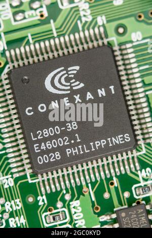 Makroaufnahme eines Mikrochips, der auf den Philippinen auf einer alten Modemkarte hergestellt wurde, mit sichtbaren Reihen von Pinouts. Chip von Conexant. Stockfoto