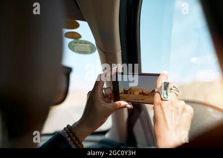 asiatische Passagierin, die ein Foto mit dem Handy aus dem Inneren eines Autos gemacht hat Stockfoto