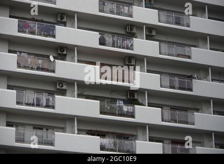 Weiße japanische Wohnungsfassade mit Klimaanlage, externer Einheit und Kleidung, die auf Balkonen hängt Stockfoto