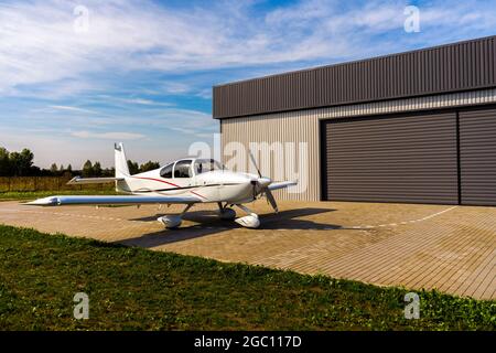 Ein kleines weißes Privatflugzeug vor dem Flug in der Nähe des Hangars. Stockfoto