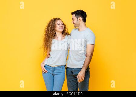 Junge glücklich interracial Millennial Paar hält und suchen einander in den Augen in isolierten gelben Studio Hintergrund Stockfoto