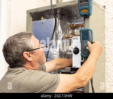Kesselinstallationsingenieur, der einen mit Heizöl befeuerten Kessel im Freien mit einem Rauchgasanalysator in Betrieb genommen hat. Stockfoto