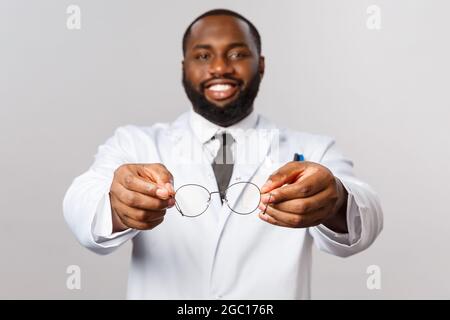 Konzept für medizinische, medizinische und Krankenhausbehandlung. Probieren Sie diese Brille aus. Portrait des gutaussehenden afroamerikanischen Optikers Tharapist Stockfoto