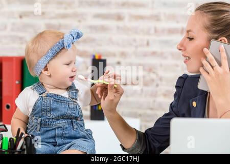 Family Business - Telearbeiter Geschäftsfrau und Mutter mit Kind macht einen Anruf Stockfoto