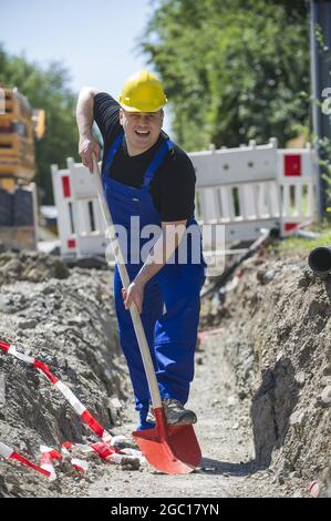 Bauarbeiter mit Schaufel in einem Nutzgraben Stockfoto