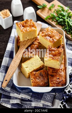 kartoffelkugel, gebackener Pudding oder Auflauf geriebener Kartoffeln in einer Auflaufform auf einem Holztisch, jüdisches Feiertagsrezept Stockfoto