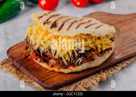 Köstliche Arepa aus geschreddertem Fleisch mit gelbem Käse Stockfoto