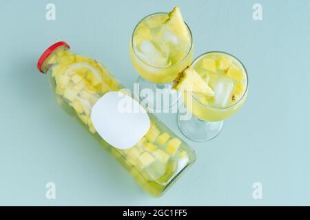 Glasflasche und zwei Gläser mit Fruchtwasser auf blauem Hintergrund. Speicherplatz kopieren. Stockfoto