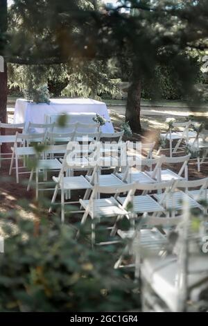 Stuhl vor dem Altar einer Hochzeit im Freien inmitten von Bäumen angeordnet. Hochzeitsdekoration im Freien Stockfoto