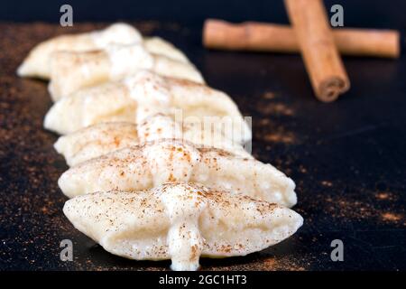 Faule Knödel auf einem Stein, gekrönt mit Vanillesoße und mit Zimt bestreut Stockfoto