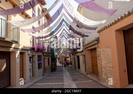 BRIHUEGA, SPANIEN - 10. JULI 2021: Enge alte Stadtstraße, die während der Blütezeit der Lavendelfelder mit violetten Shadern bedeckt ist, Brihuega, Guadalajara, Stockfoto