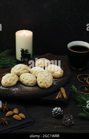 Kekse auf einem Holzbrett, eine Tasse Kaffee, Zitronenscheiben, Zimtstangen, Waldkegel, Gewürze, Nüsse und Wacholderzweige auf einem Pinien-Brett-Tisch Stockfoto