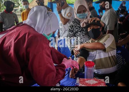 Kendari, Indonesien. August 2021. Ein Gesundheitsmitarbeiter verabreicht einem behinderten Mann eine Dosis Sinovac COVID-19-Impfstoff.die Polizeiimpfstelle Kendari führte eine Impfoperation für Menschen mit Behinderungen auf der Polizeiwache Poasia in Kendari durch. Dutzende von behinderten Personen wurden in ihren jeweiligen Häusern mit Polizeifahrzeugen für ihre erste Dosis des Sinovac-Covid-19-Impfstoffs abgeholt. Kredit: SOPA Images Limited/Alamy Live Nachrichten Stockfoto