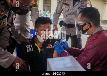 Kendari, Indonesien. August 2021. Ein Gesundheitsmitarbeiter verabreicht einem behinderten Mann eine Dosis Sinovac COVID-19-Impfstoff.die Polizeiimpfstelle Kendari führte eine Impfoperation für Menschen mit Behinderungen auf der Polizeiwache Poasia in Kendari durch. Dutzende von behinderten Personen wurden in ihren jeweiligen Häusern mit Polizeifahrzeugen für ihre erste Dosis des Sinovac-Covid-19-Impfstoffs abgeholt. Kredit: SOPA Images Limited/Alamy Live Nachrichten Stockfoto