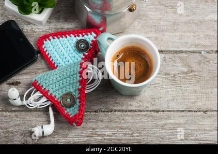 Niedlicher gestrickter Ohrkissen-Halter auf Holztisch. Life Style Set mit einer Tasse Kaffee Stockfoto