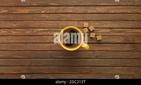 Gelbe Tasse mit heißem schwarzem Kaffee auf einem Holztisch aus echten Texturplatten. Draufsicht mit Platz für Text und jedes Design. Stockfoto