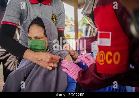 Kendari, Indonesien. August 2021. Ein Gesundheitshelfer verabreicht einer behinderten Frau eine Dosis des Sinovac COVID-19-Impfstoffes.die Polizeiimpfstelle Kendari führte eine Impfoperation für Menschen mit Behinderungen auf der Polizeiwache Poasia in Kendari durch. Dutzende von behinderten Personen wurden in ihren jeweiligen Häusern mit Polizeifahrzeugen für ihre erste Dosis des Sinovac-Covid-19-Impfstoffs abgeholt. (Foto von Andry Denisah/SOPA Images/Sipa USA) Quelle: SIPA USA/Alamy Live News Stockfoto