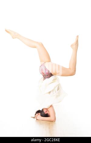 Portrait einer schönen eleganten schlanken aktiven sportlichen jungen Frau, die im Yoga-Studio auf dem Kopf steht, Yoga-Pose übt. Gesunder, aktiver Lebensstil Stockfoto