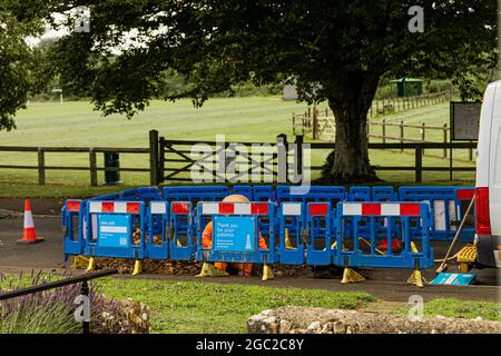 Männer bei der Arbeit, die eine undichte Wasserleitung in einem ländlichen Dorf im Südwesten Großbritanniens reparieren Stockfoto