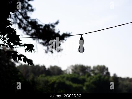 Die Glaslampe Lampe Bulb Silhouette auf Straße Draht. Straßenbeleuchtung. Energiesparendes Licht Stockfoto